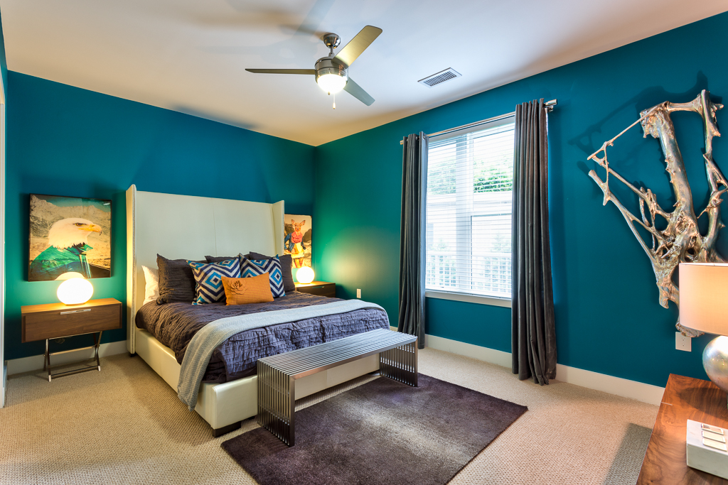 Bedroom with carpet flooring, ceiling fan, lamps, accent walls, and wall decor