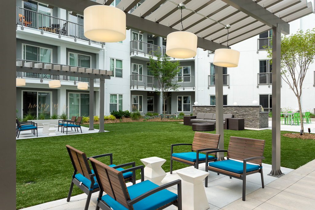 Outdoor clubhouse deck with shaded seating, couch, and garden area