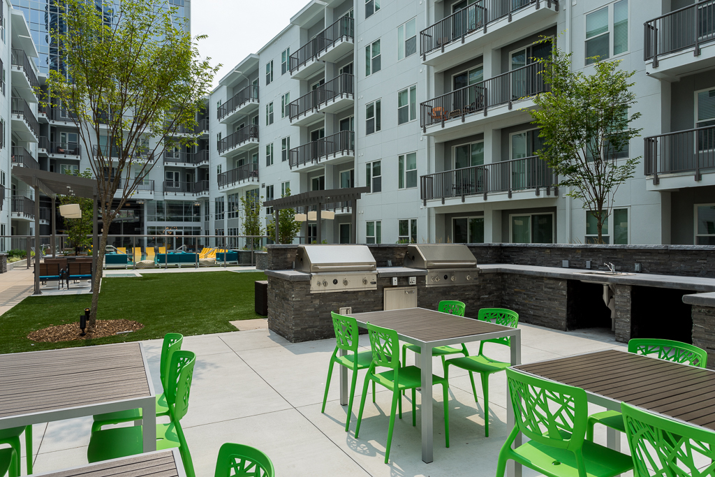 Outdoor clubhouse deck area with table seating, grilling stations, and garden access