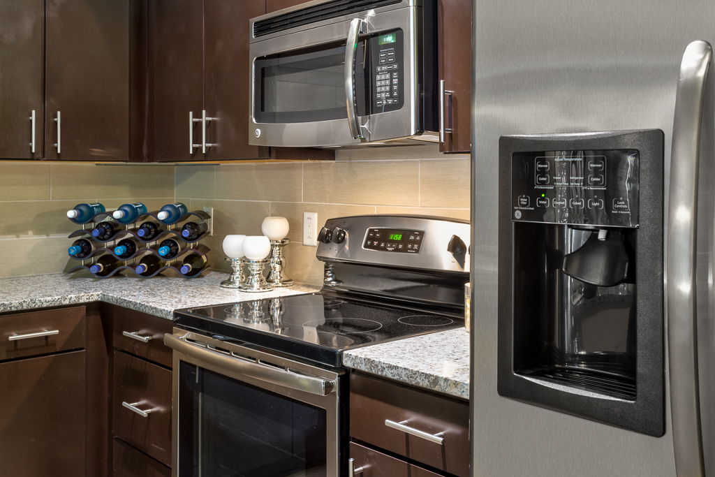 Kitchen area with granite countertops, steel oven, steel microwave, and steel refrigerator