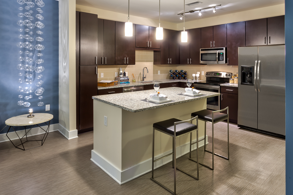 Kitchen area with granite countertops, island seating, steel appliances, and wood-style flooring