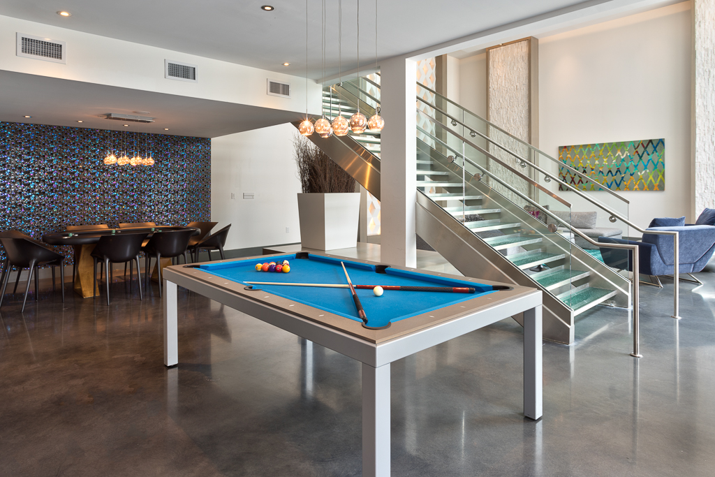 Indoor clubhouse lounging area with pool and poker tables, and stair access to second level