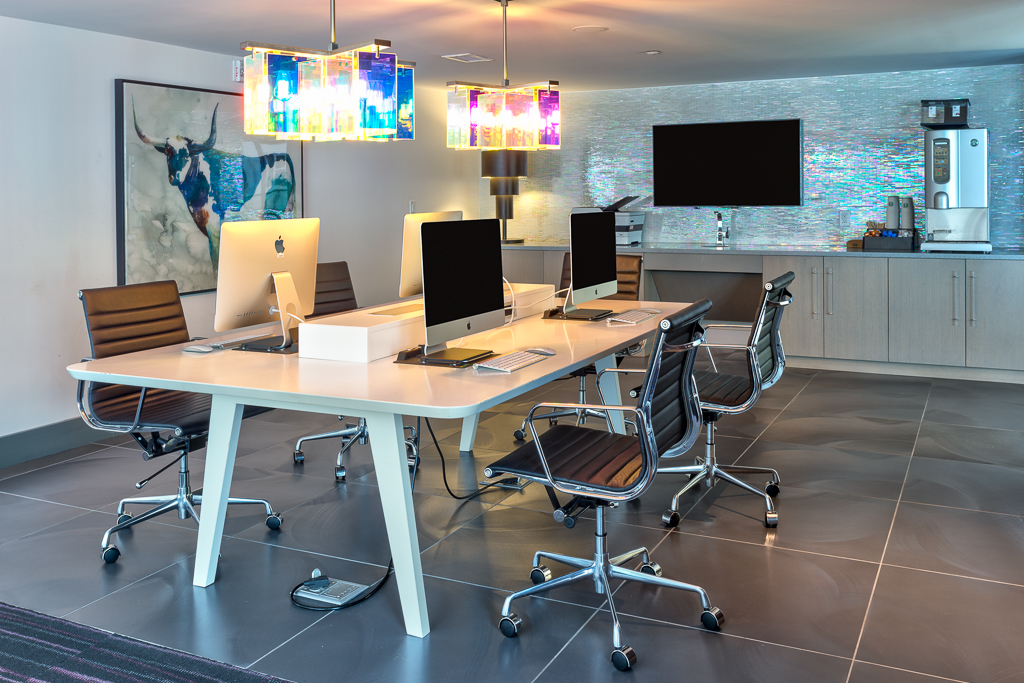 Indoor workspace meeting room with computers, TV, and dining bar